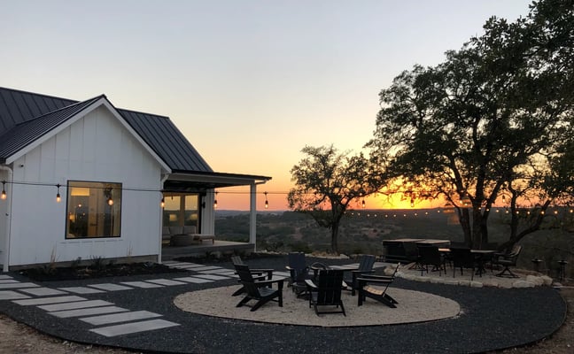 Open-plan kitchen and living room with island, pendant lights, hardwood floors, and panoramic valley views through large windows